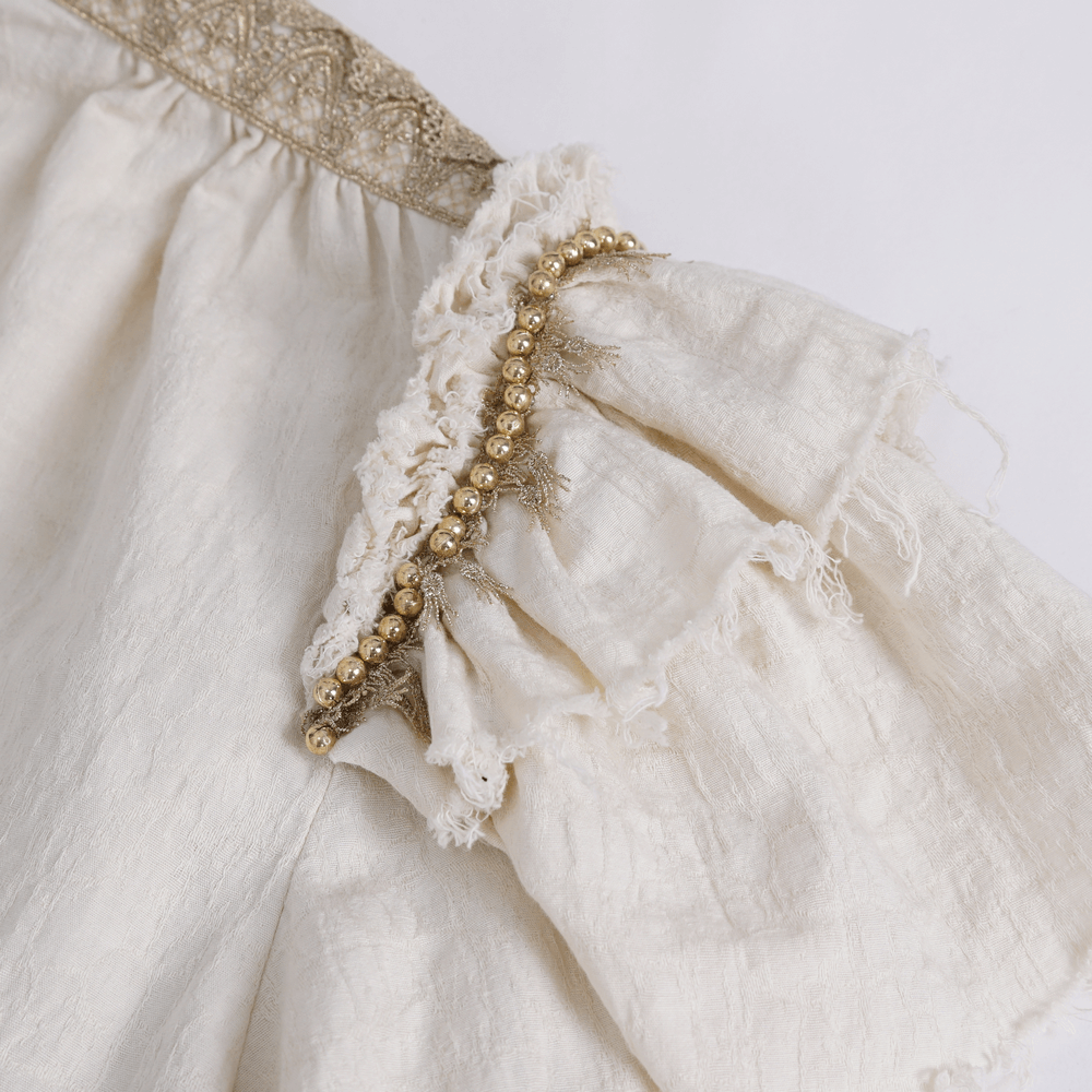Close-up of elegant ruffled cotton shirt showing beaded details and vintage lace accents.