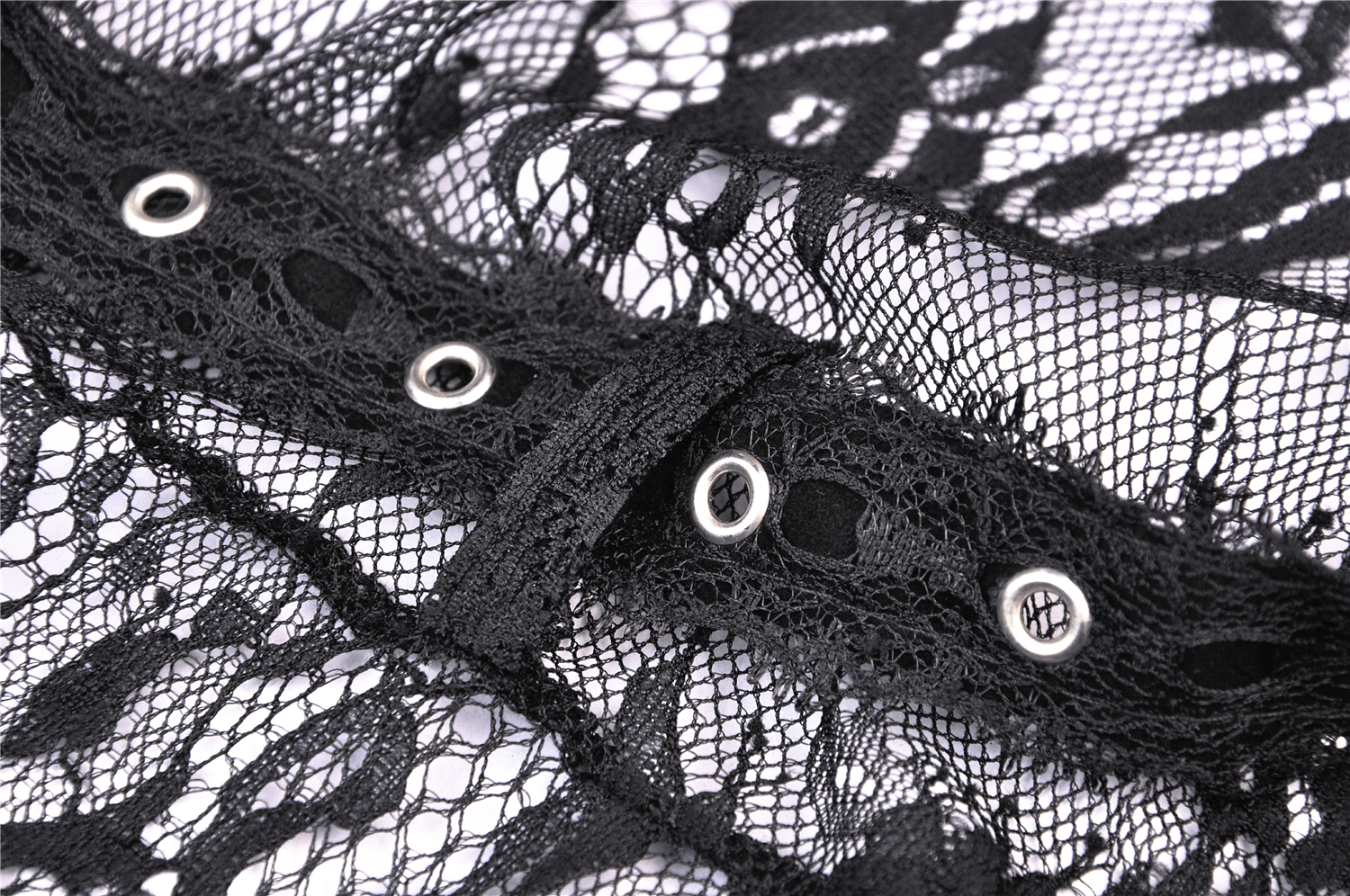 Close-up of elegant black lace fabric with eyelets and fringe detail for a sexy cape design.