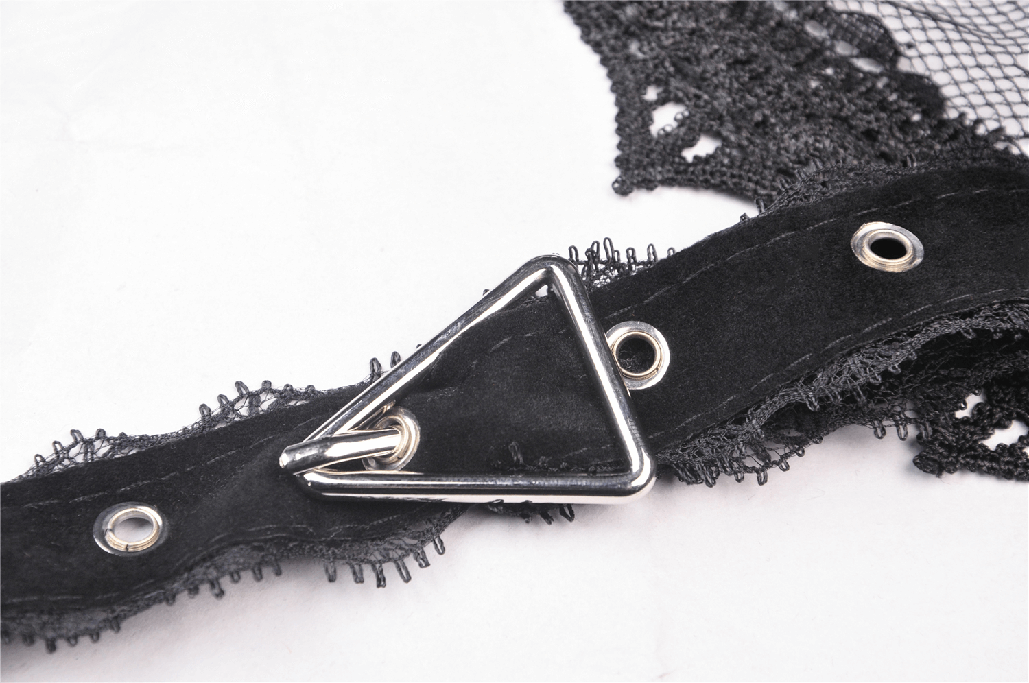 Close-up of black lace fabric and metal hook detail for sophisticated gothic fashion accessories.