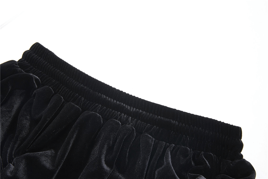 Close-up of the elastic waistband of an elegant black velvet skirt, showcasing luxurious texture and ruffled design.