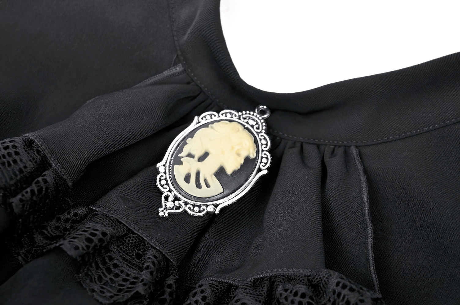 Close-up of elegant ruffle dress neckline featuring ornate brooch accent and intricate lace details.