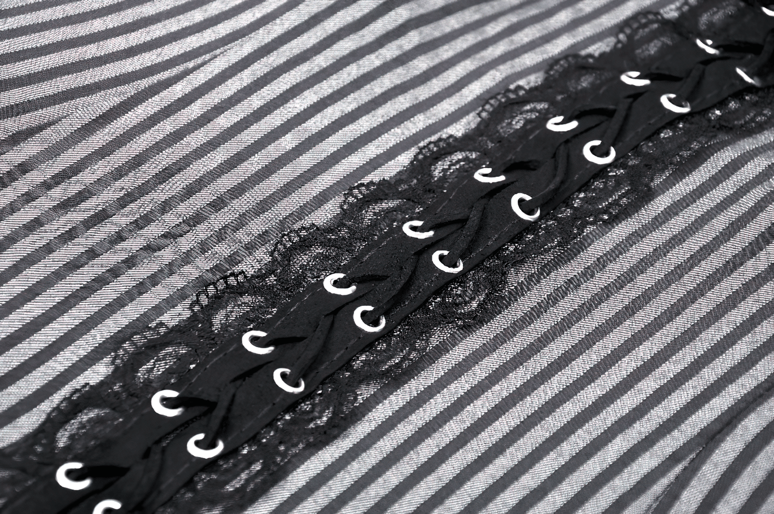 Close-up of elegant striped dress fabric with ruffles and brooch accent, showcasing lace and eye-catching details.