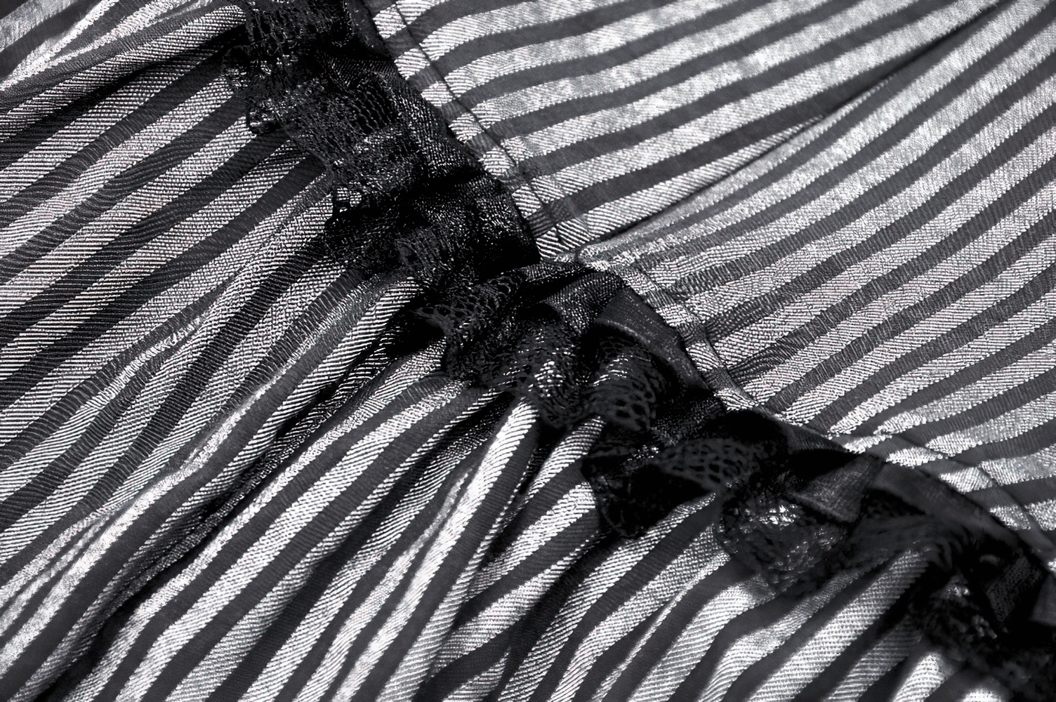 Close-up of elegant striped fabric with ruffle detail for the chic sleeveless dress with brooch accent.