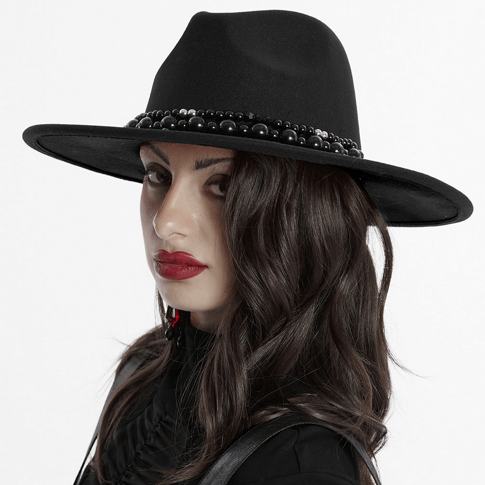 Elegant black suede wide-brim hat with pearl accents and Gothic style, worn by a model with striking red lips.