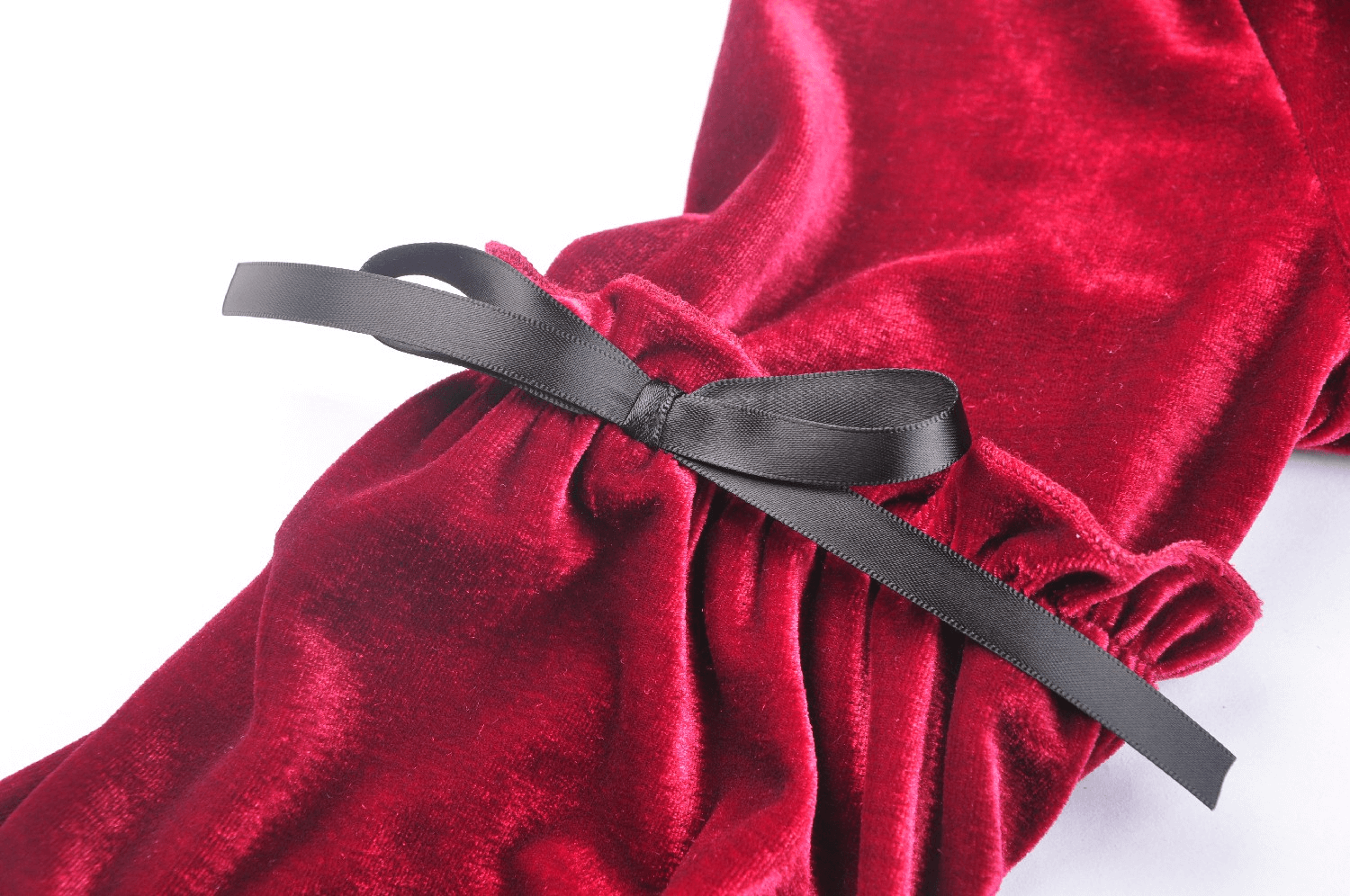Close-up of a red velvet dress sleeve with a black ribbon bow detail, showcasing elegant gothic fashion.