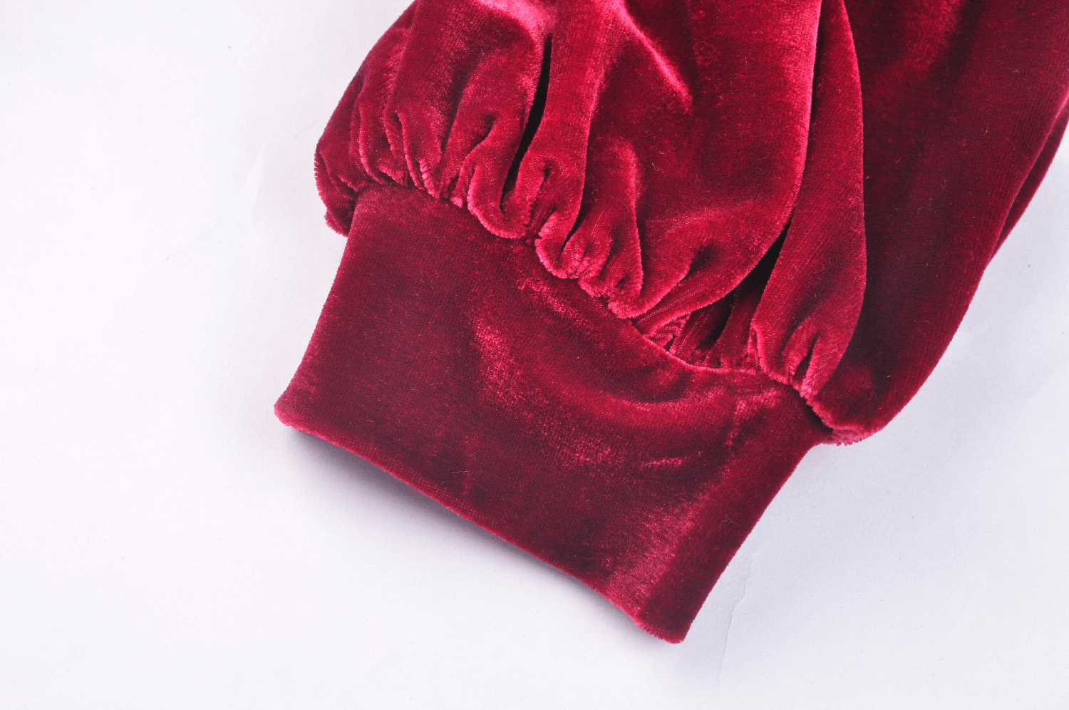 Close-up of the elegant red velvet sleeve of a Gothic dress, showcasing soft texture and gathered detailing.