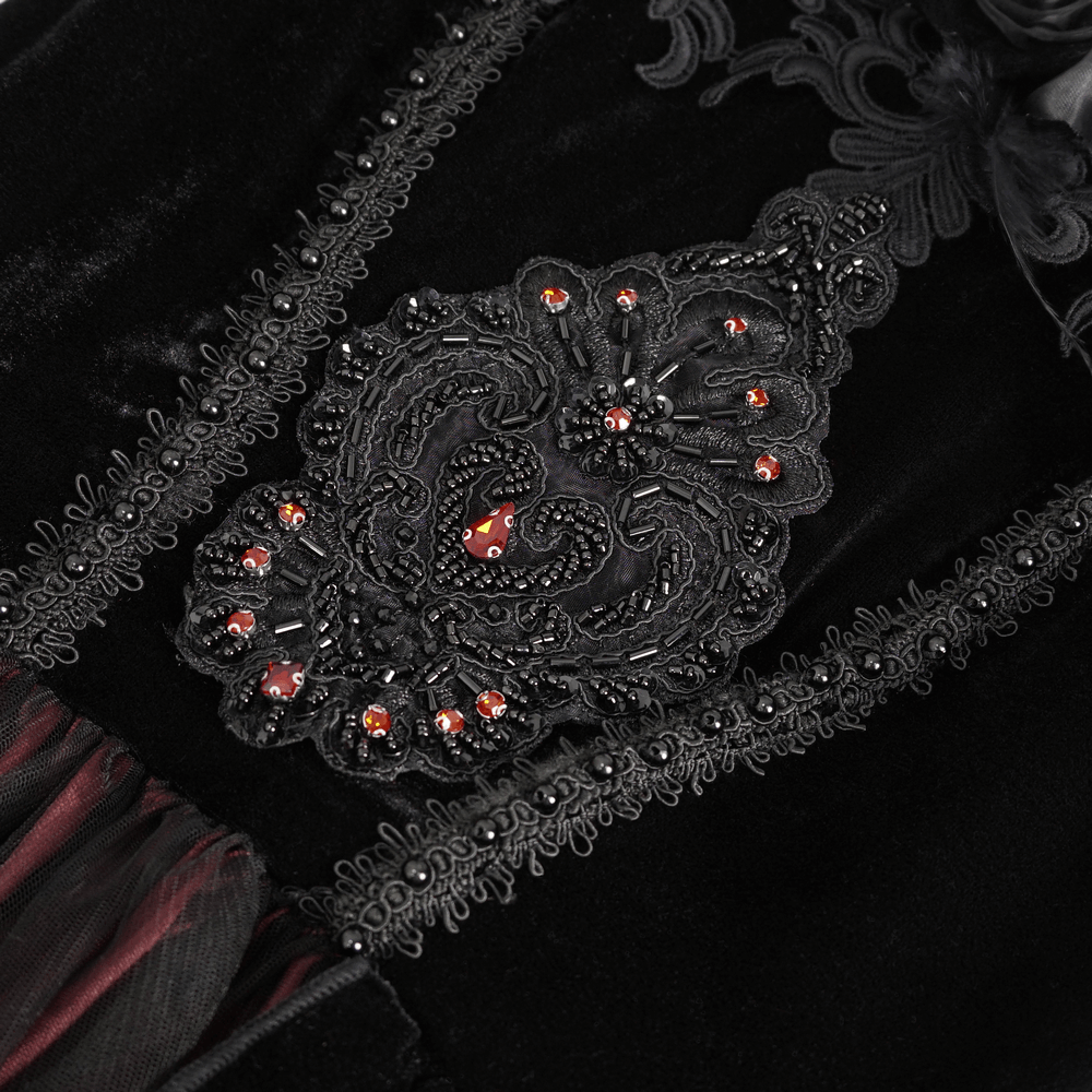 Close-up of intricate black velvet dress detailing with red gem accents, highlighting Victorian gothic elegance.