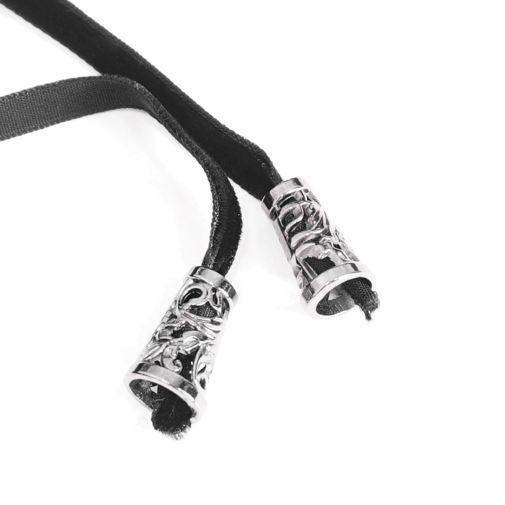 Intricate silver decorative tips on black ribbon laces, perfect for Victorian-inspired fashion accessories.