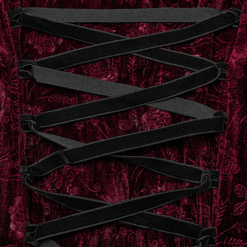 Close-up of intricate lace-up detailing on a rich velvet dress, showcasing elegant floral textures and deep burgundy color.