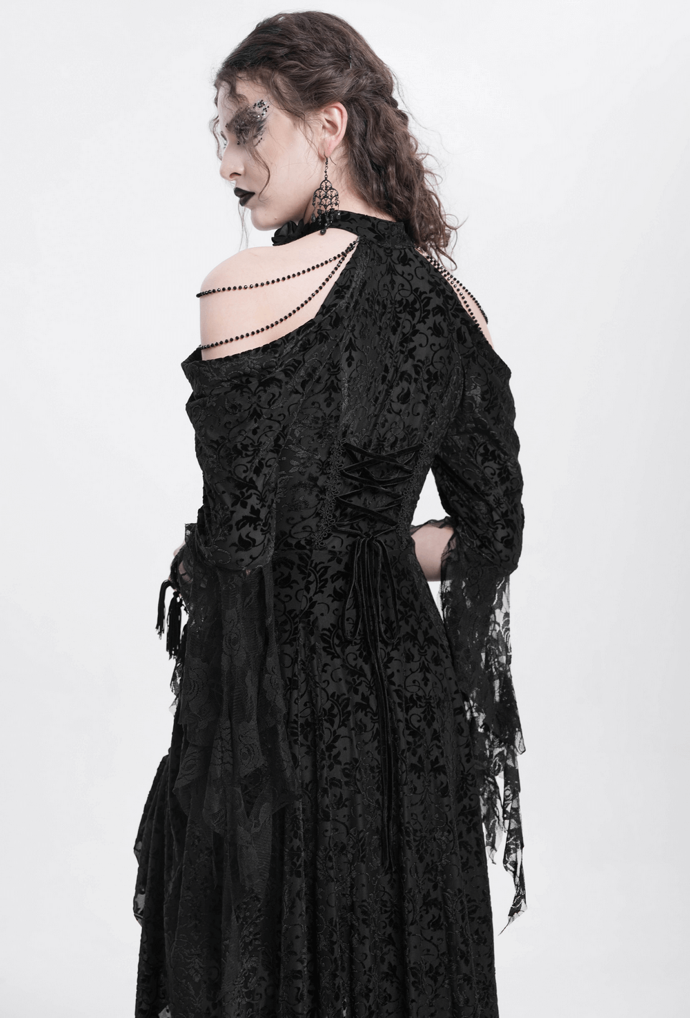 Back view of a model wearing an elegant black Victorian lace gothic dress with ruffled sleeves and intricate details.