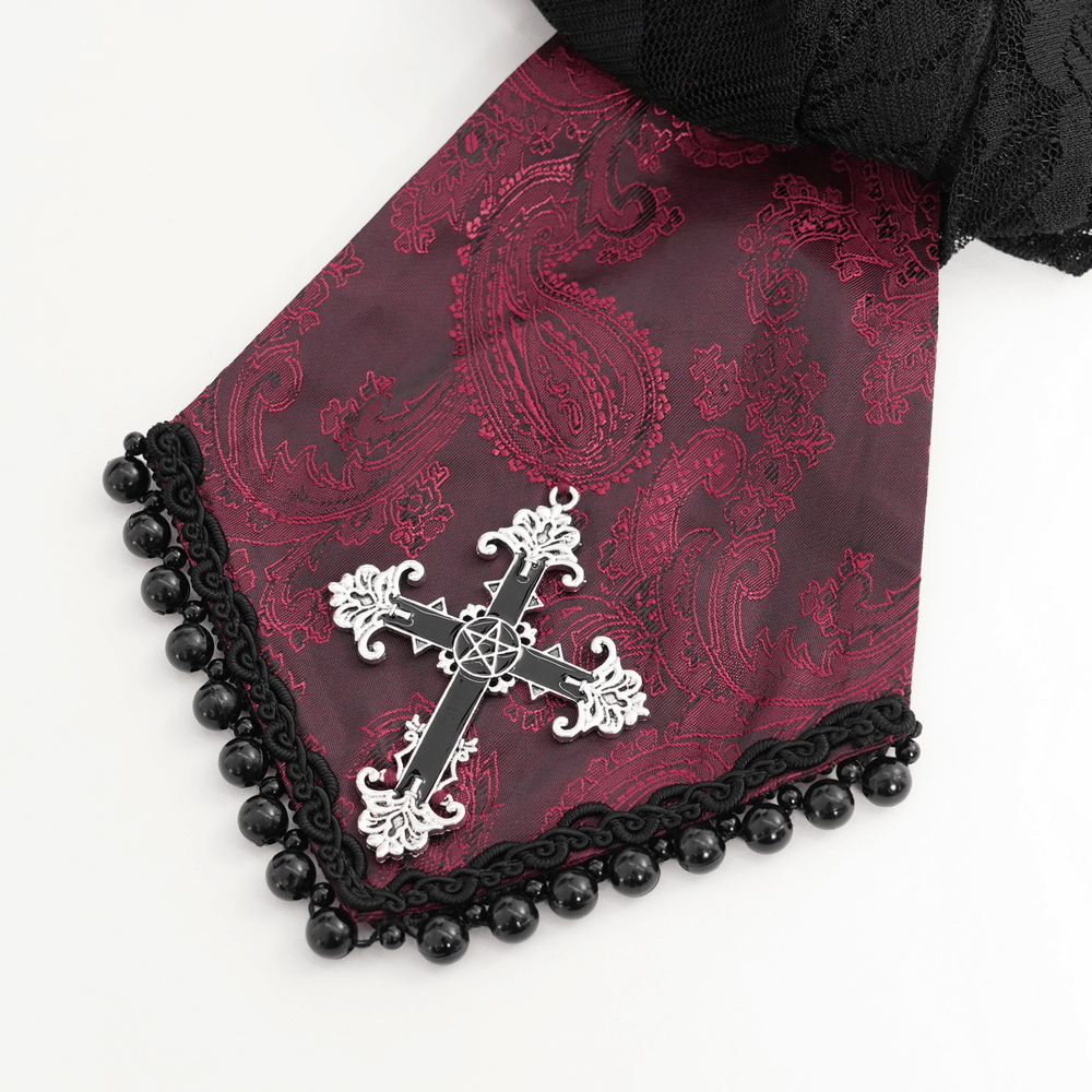 Close-up of elegant ruffled lace collar with a black cross brooch on wine red fabric, perfect for gothic style.