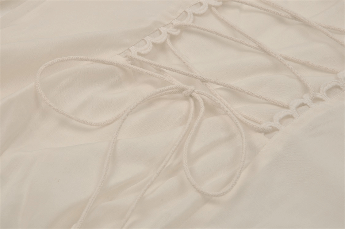 Close-up of intricate lace detailing and ties on an elegant ivory Victorian-inspired maxi dress.