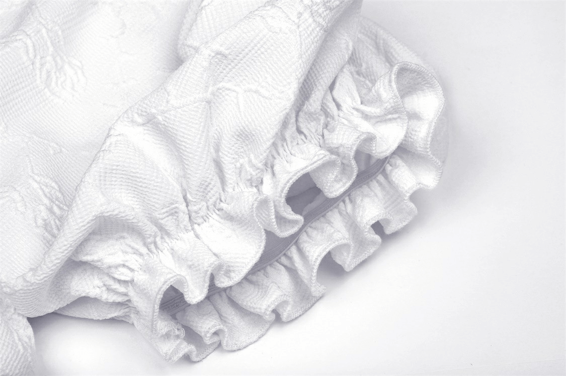 Close-up of elegant white dress details featuring lace and puff sleeve ruffles.