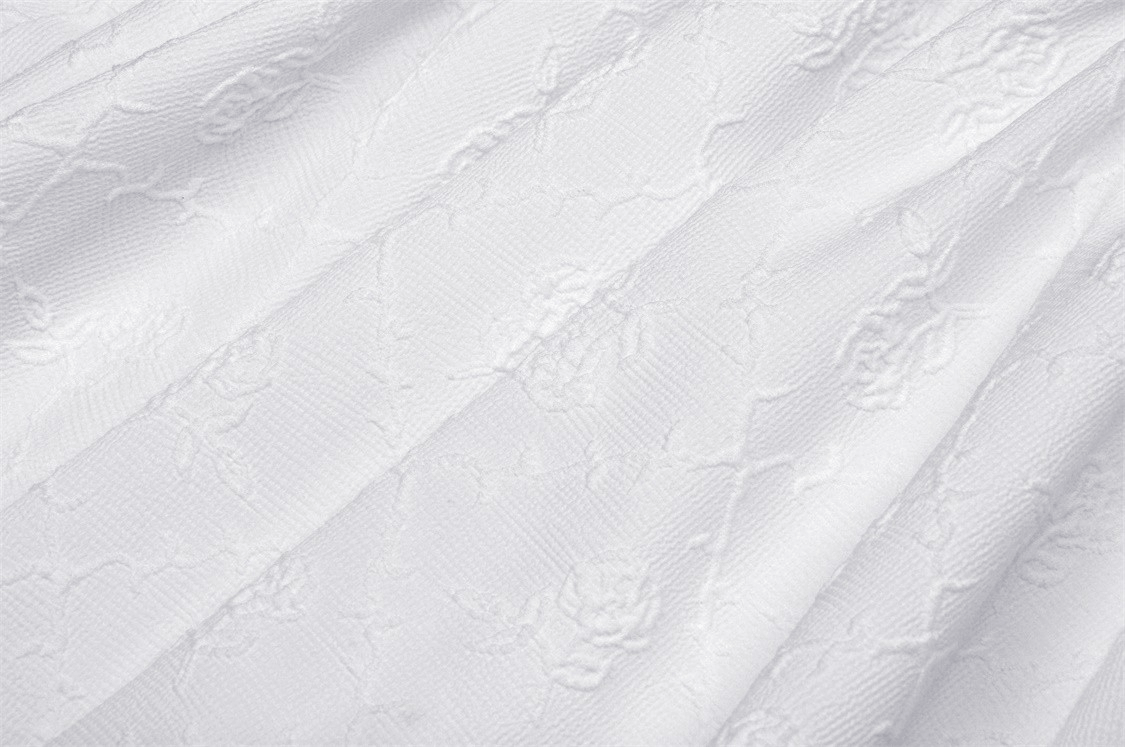 Close-up of elegant white fabric with floral embroidery and lace texture, perfect for bridal gowns.