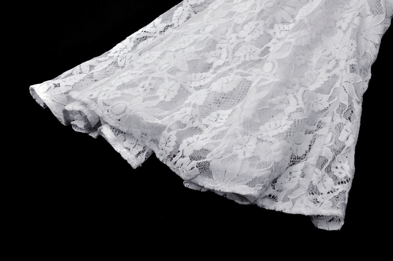 Elegant white lace fabric of a mermaid dress with intricate patterns, showcasing a chic and delicate design.