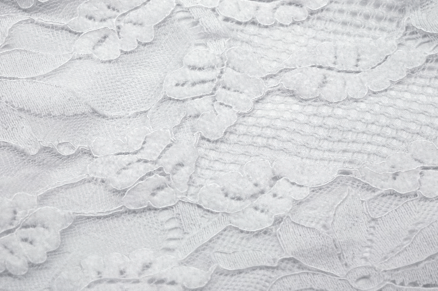 Close-up of elegant white lace fabric with intricate floral patterns and soft textures, perfect for chic gown designs.