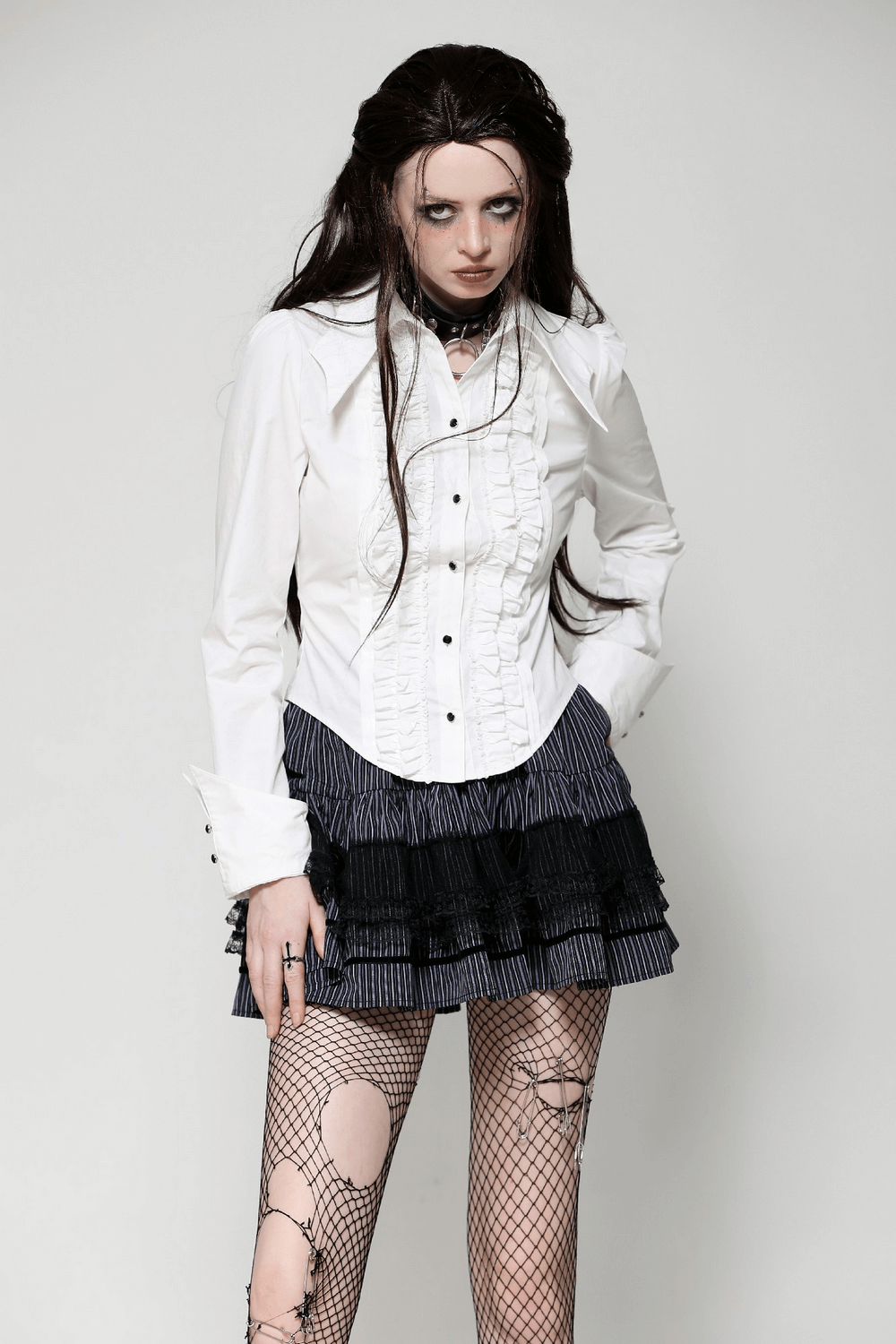 Elegant white ruffled blouse with button detailing paired with a stylish black skirt and fishnet tights.