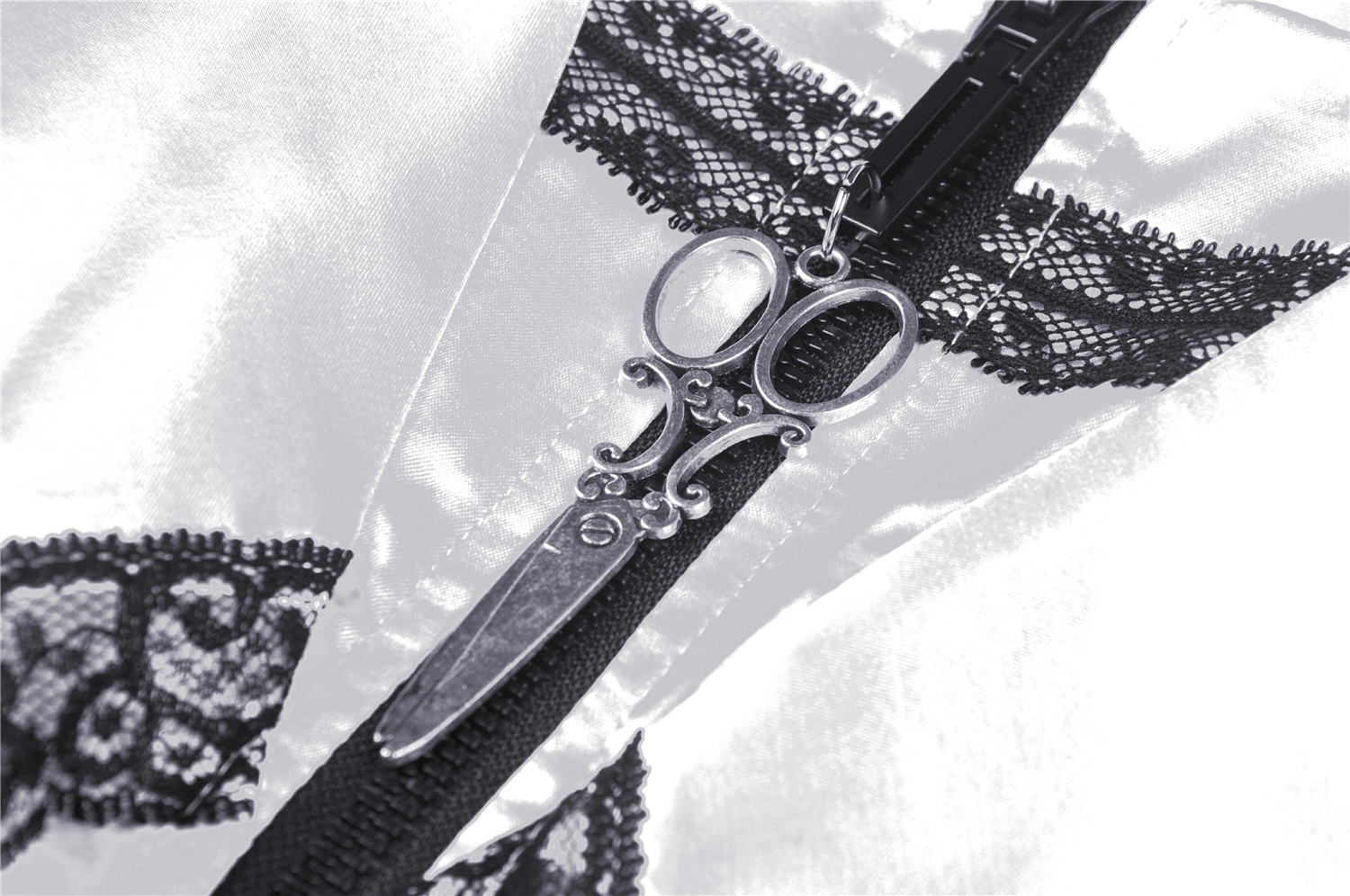 Close-up of elegant white satin dress with black lace and scissor zipper detail, showcasing its unique design.