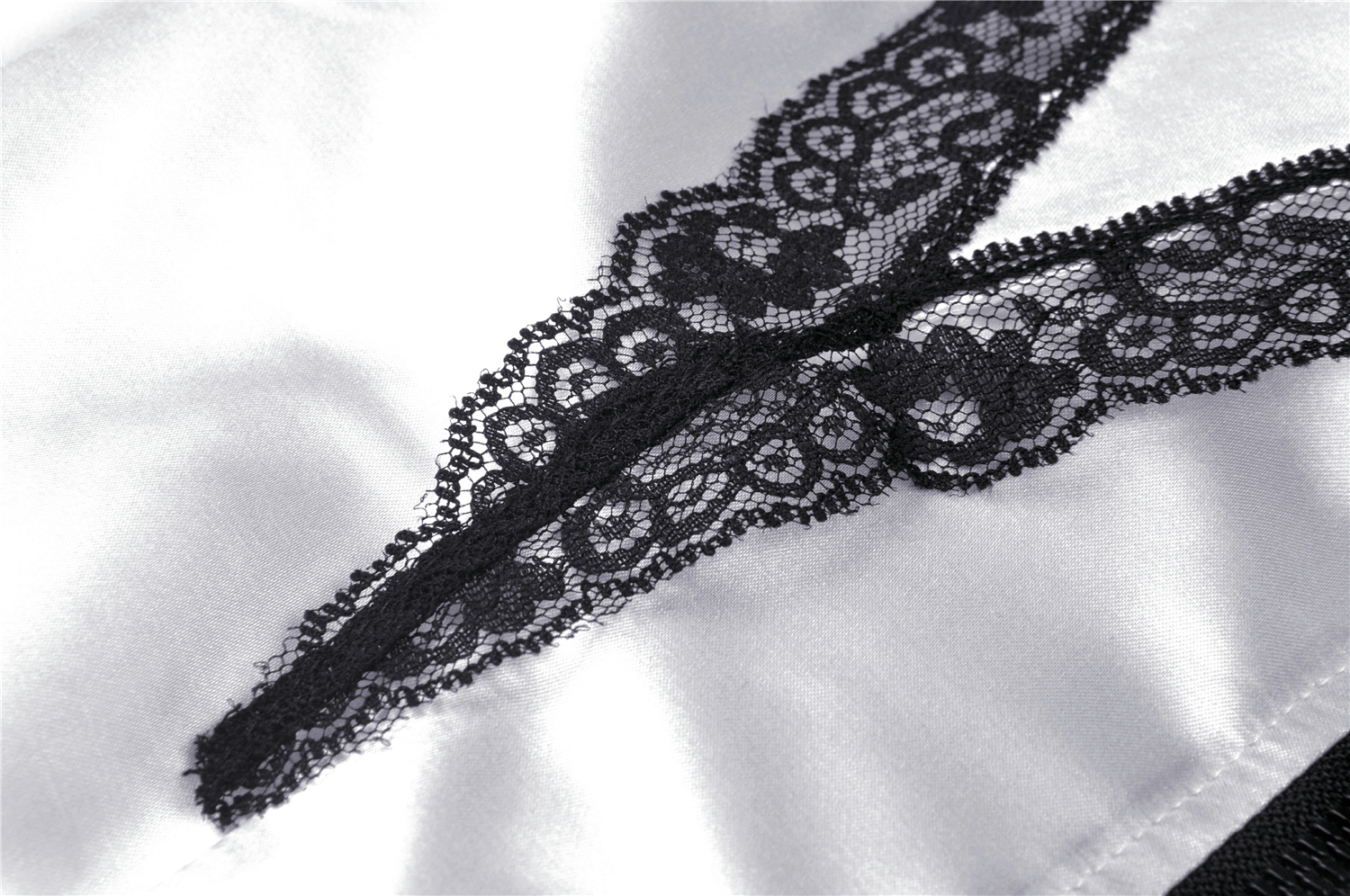 Close-up of elegant white satin fabric with delicate black lace detailing, showcasing a stylish and sophisticated design.