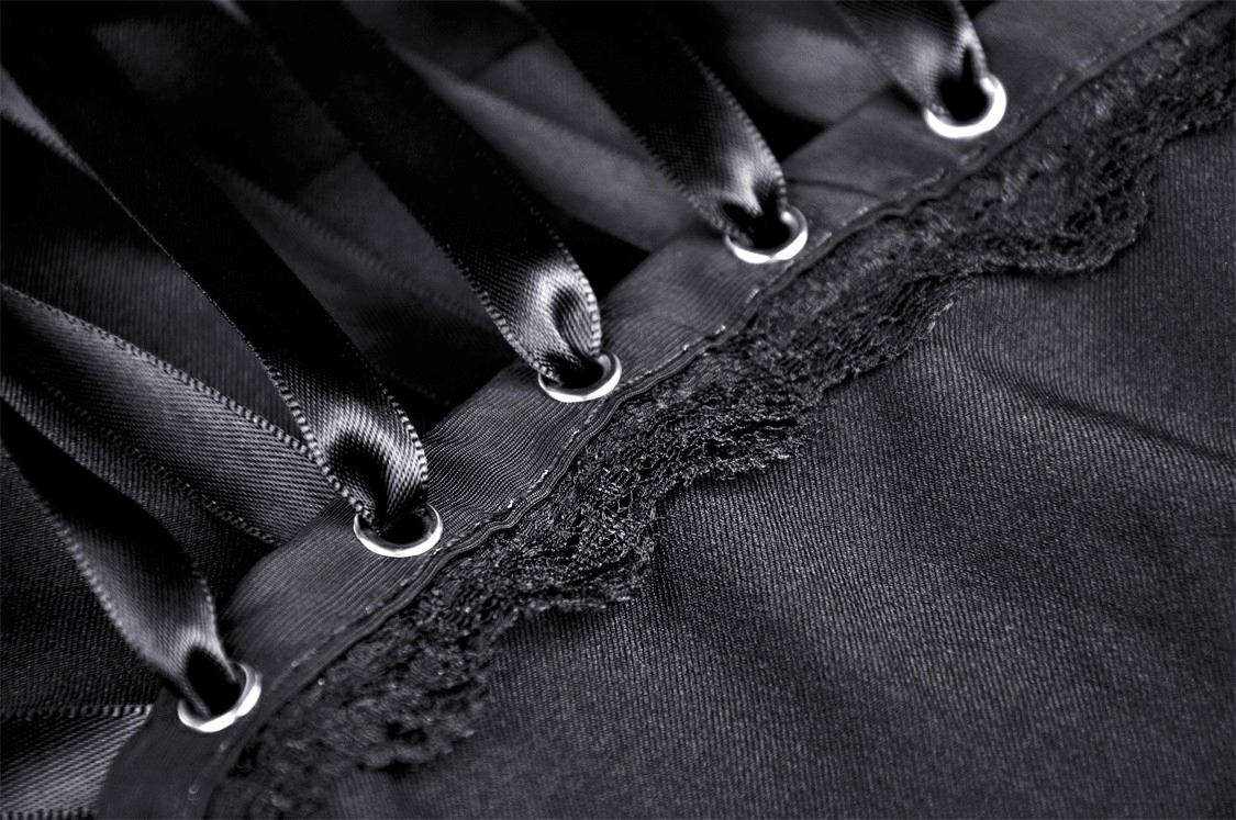 Close-up of elegant black dress detailing featuring satin ribbons and lace trim, showcasing its sophisticated design.