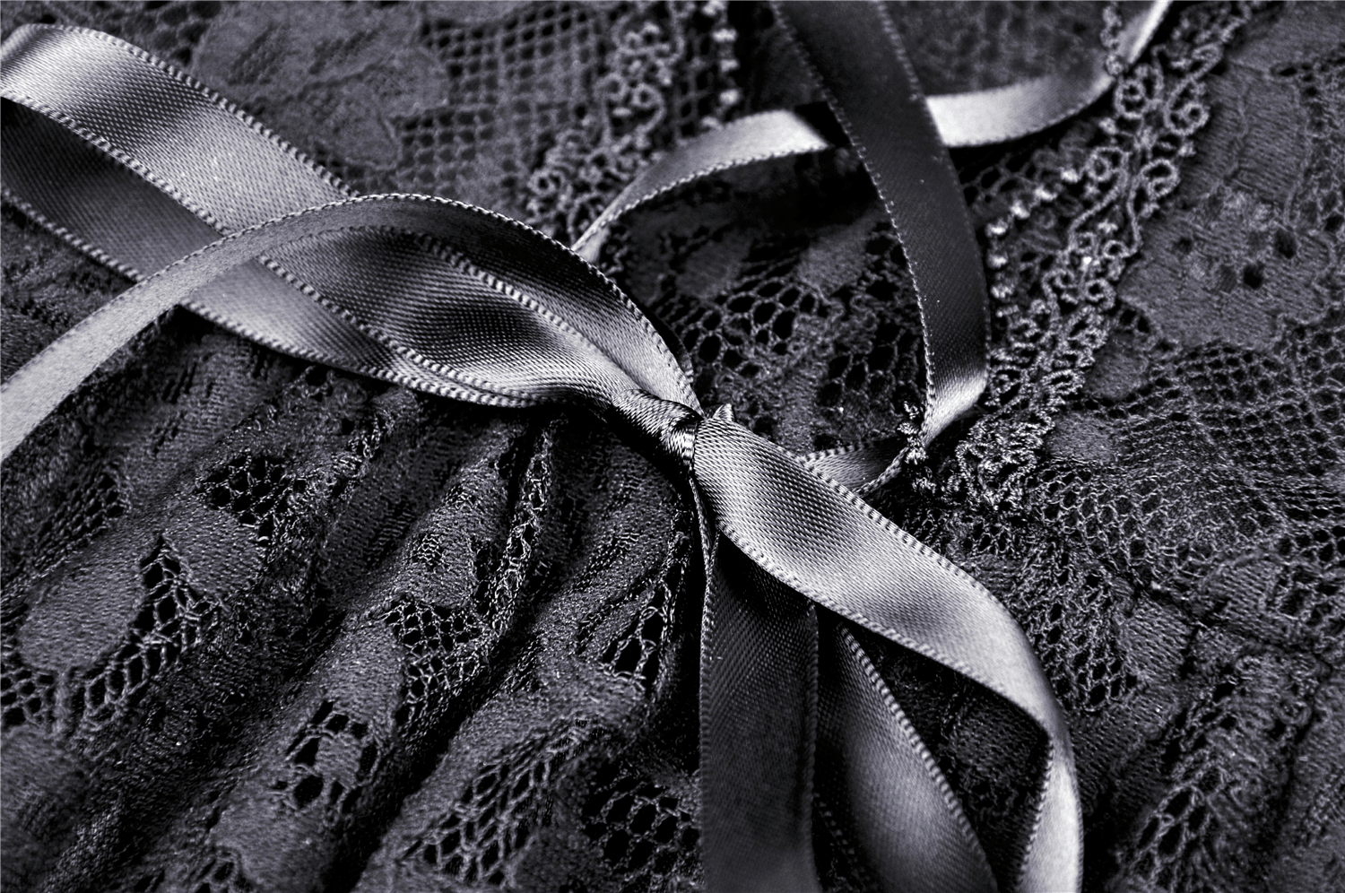 Close-up of black lace fabric with elegant ribbon detail, showcasing intricate patterns and vintage style.