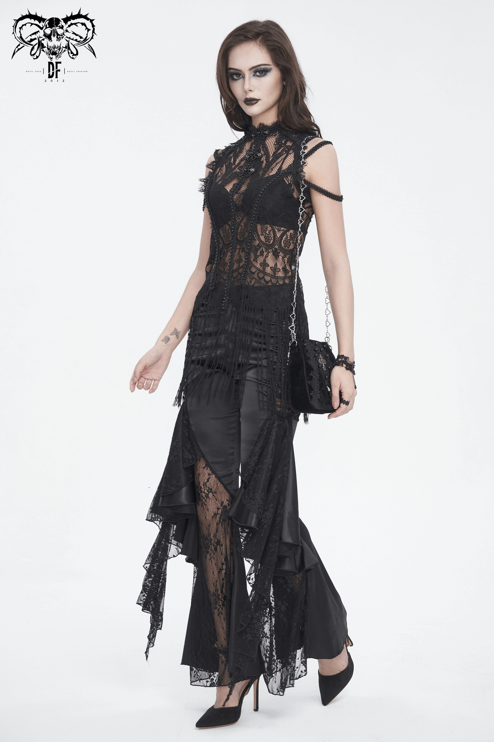 Gothic woman in layer lace dress and black velvet shoulder bag, showcasing edgy style and elegance.