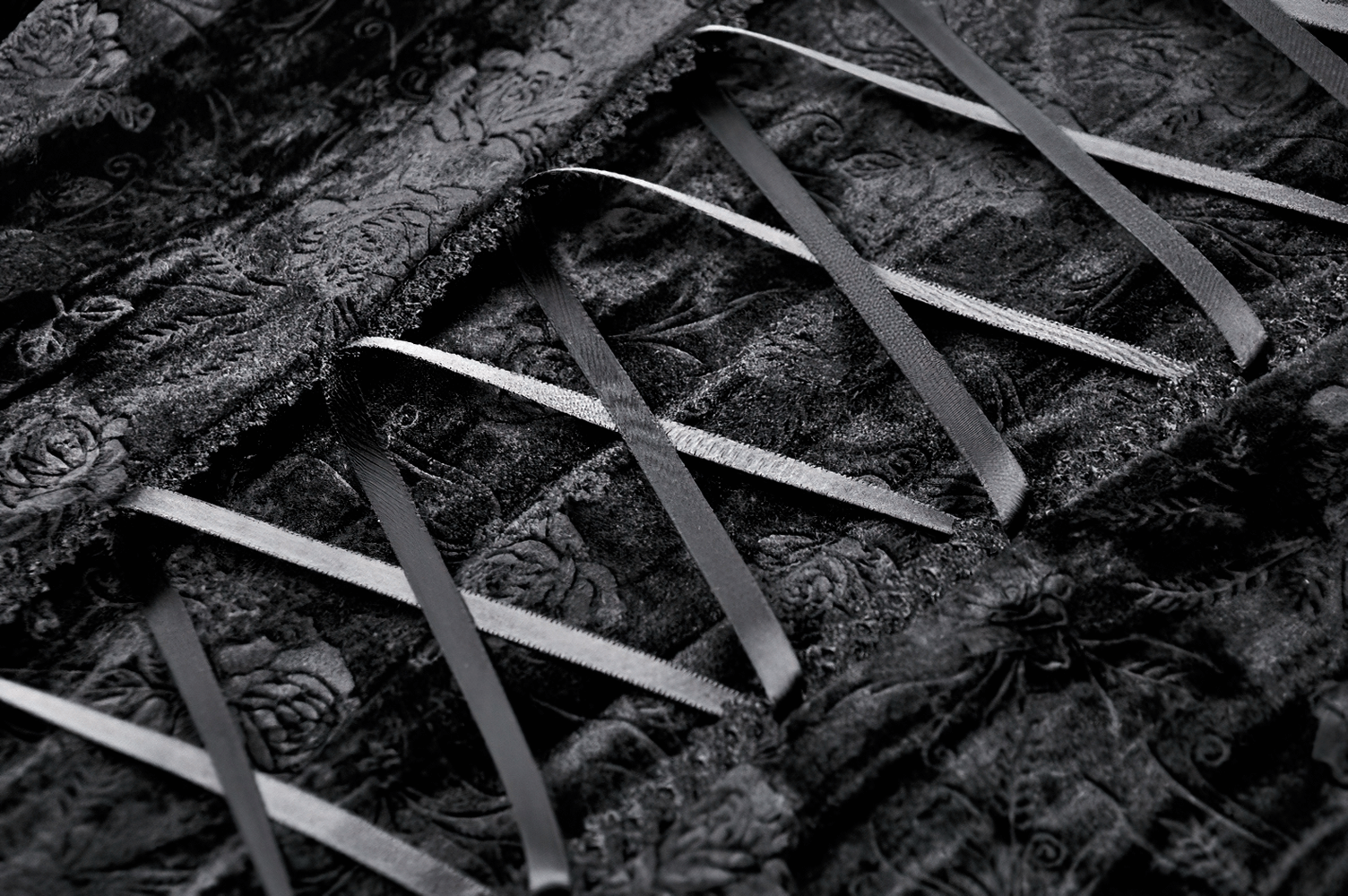 Close-up of velvet lace-up details with black ribbon, showcasing elegant Victorian-style craftsmanship.