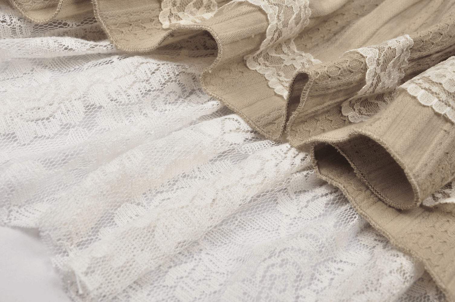 Close-up of an elegant beige layered skirt featuring intricate lace details and ruffled design, perfect for women's fashion.