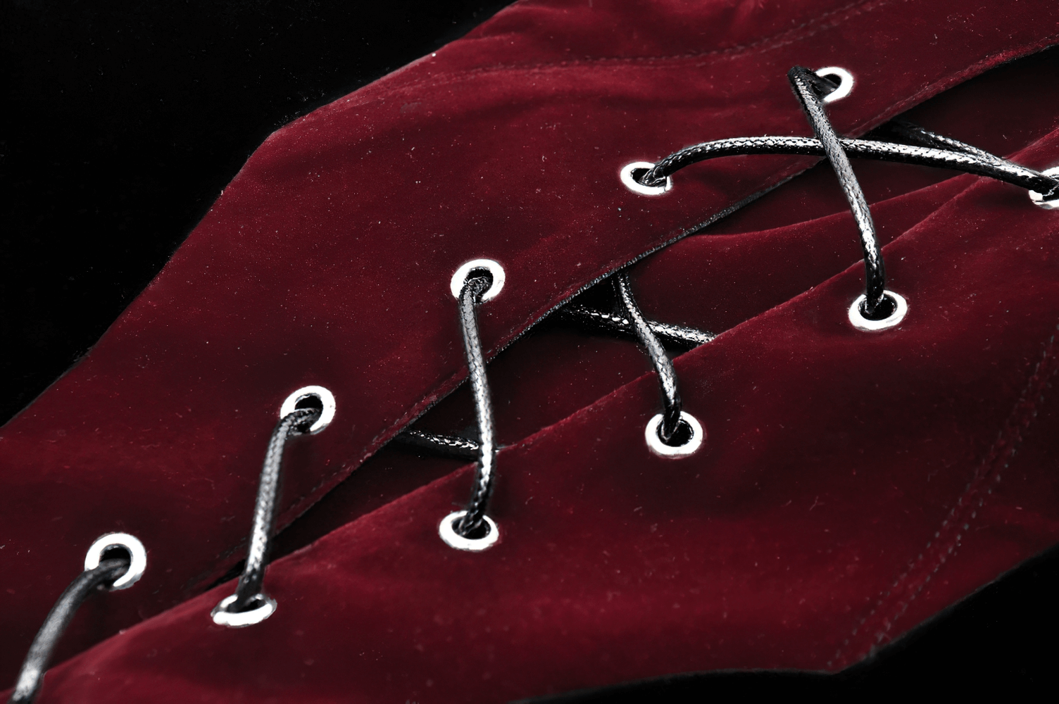 Close-up of a wine-red velvet corset lace-up detail showcasing silver eyelets and black laces for a dramatic look.