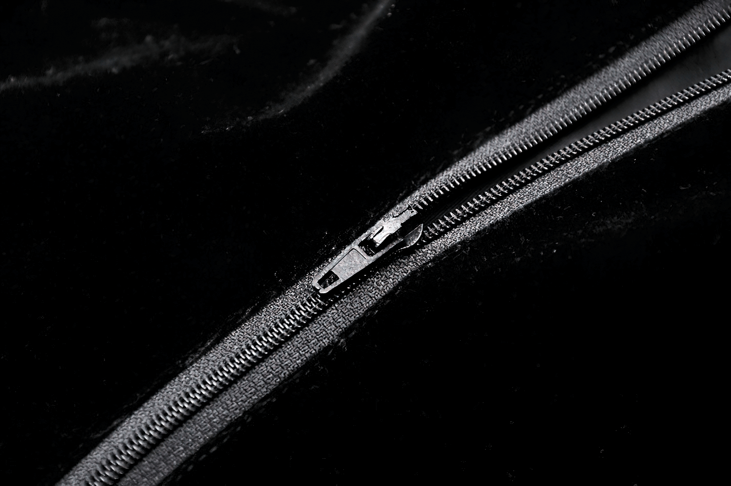 Close-up of a sleek black zipper on a luxurious velvet fabric, adding elegance to any outfit.