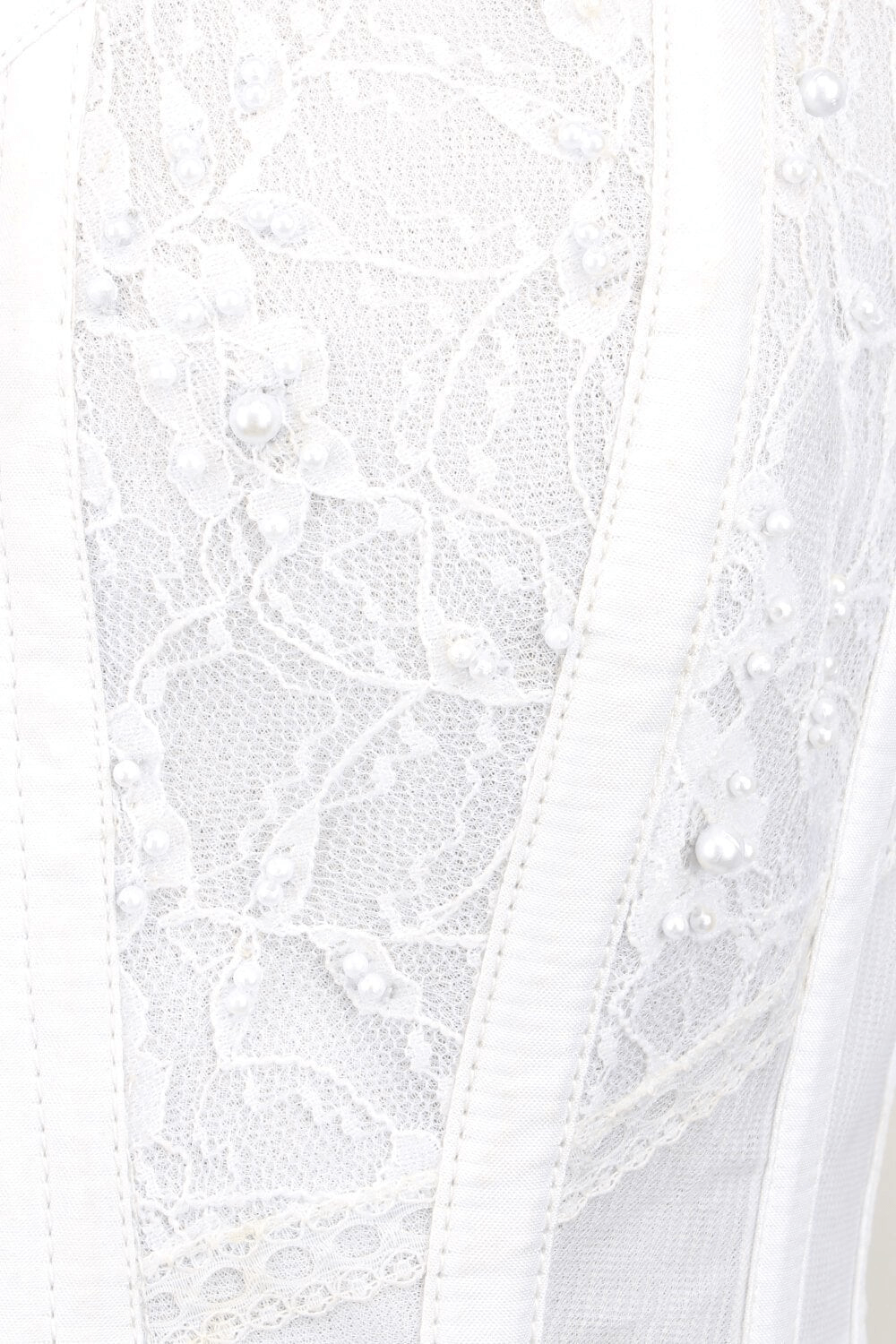 Close-up of elegant white bridal corset featuring lace overlay and pearl details, perfect for weddings and special occasions.