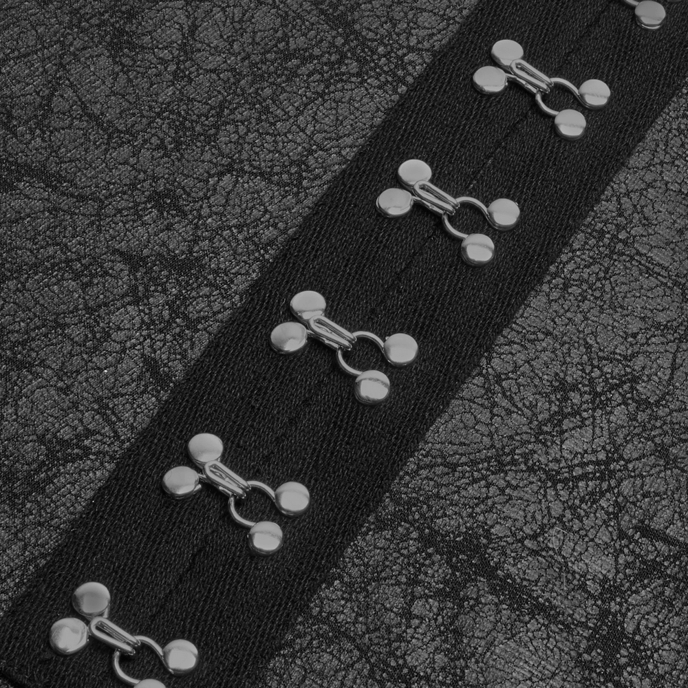Close-up of textured black fabric with decorative silver fasteners on a punk-style coat.
