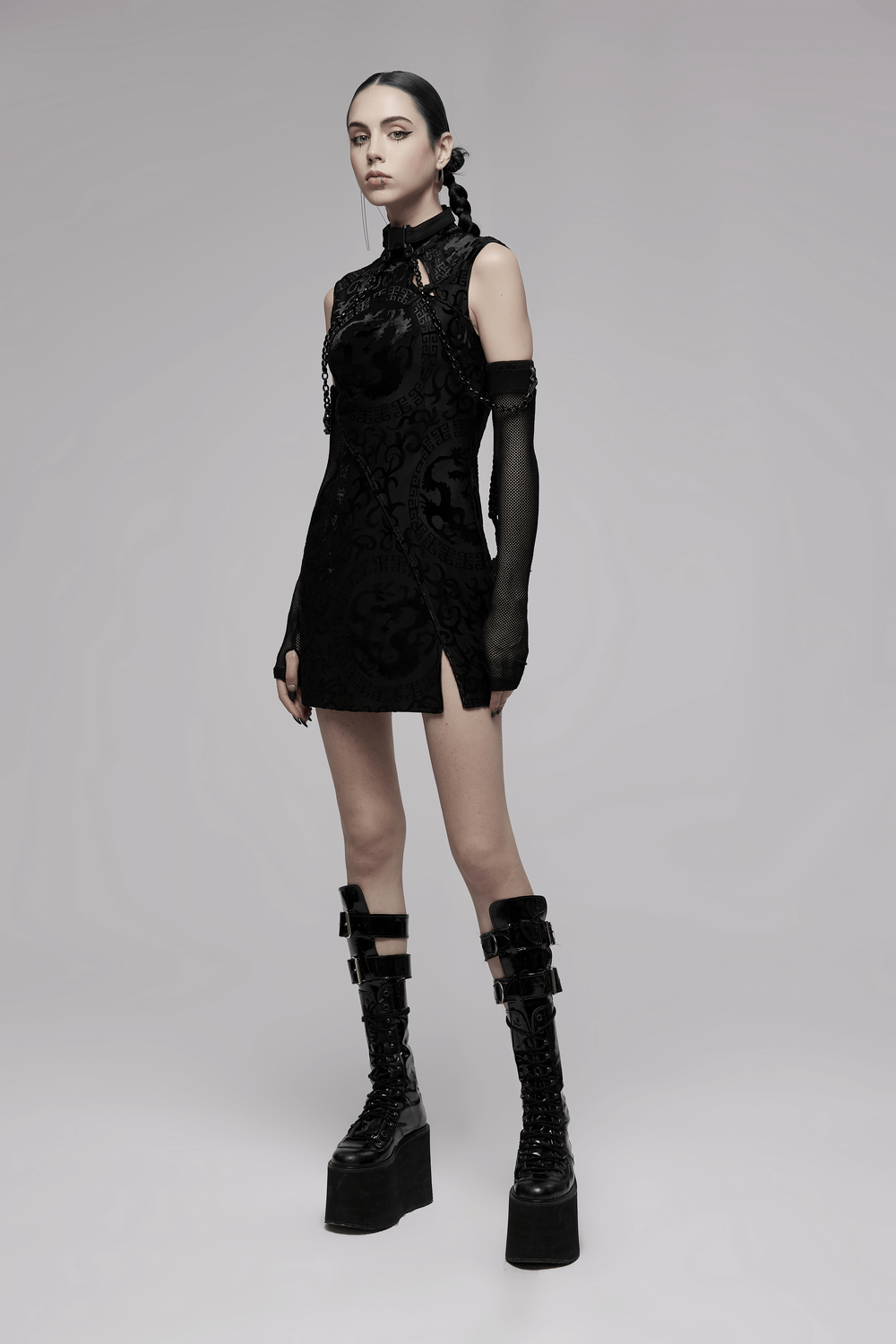 Model showcasing a black embroidered dragon A-line dress with stylish platform boots and a sleek silhouette.