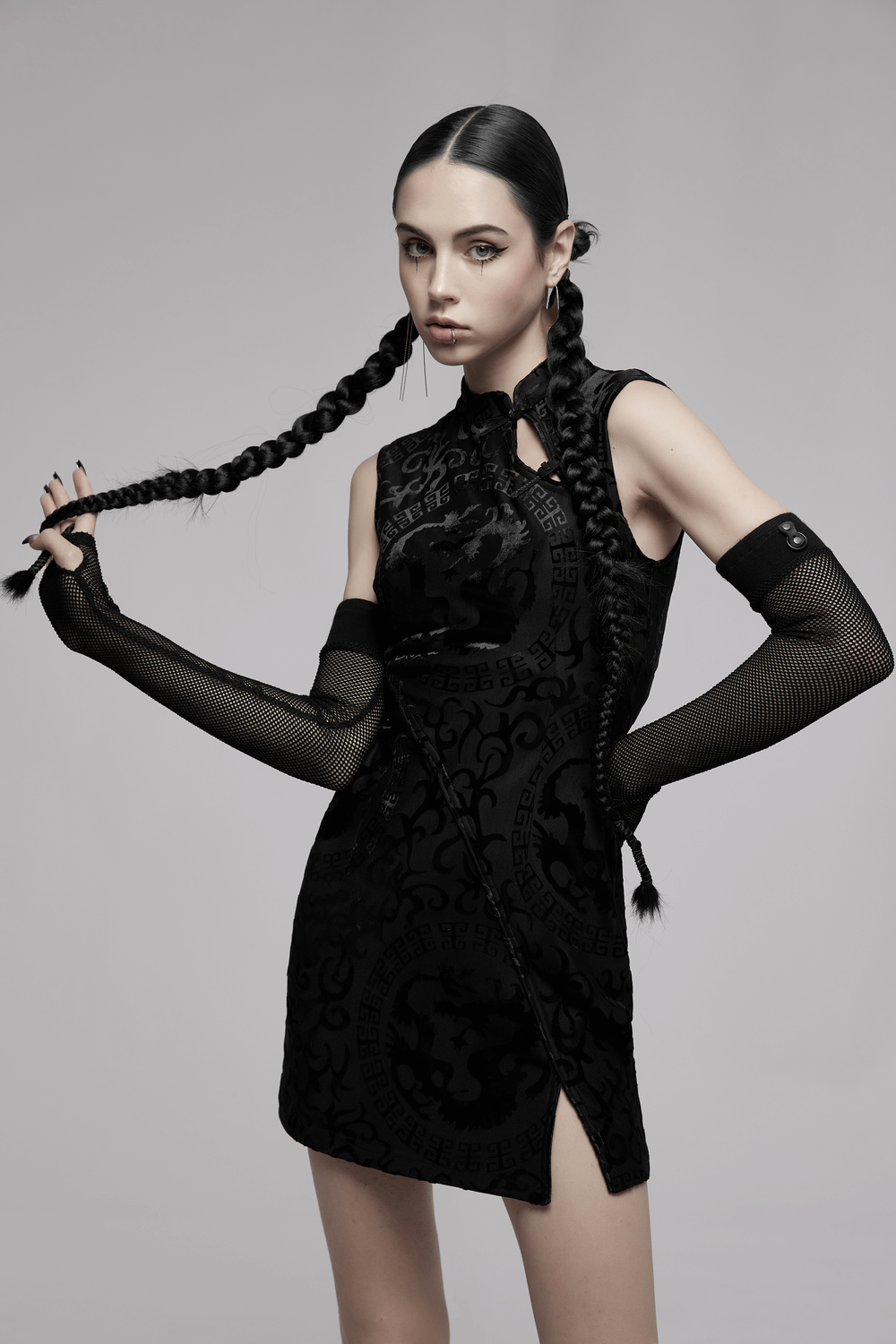 Model showcasing an embroidered dragon A-line dress in stretch velvet with stylish accents and a trendy hem split.