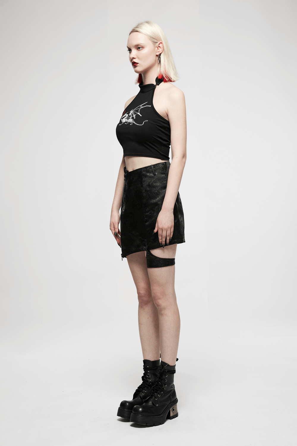 Model showcasing an embroidered dragon asymmetrical skirt with garters and a black crop top, exuding edgy fashion.