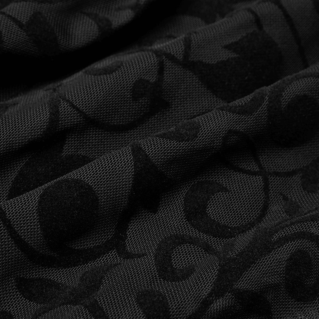 Close-up of luxurious black flocking net fabric with intricate embroidered floral patterns.