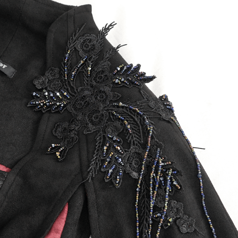 Intricate black embroidery on shoulder of gothic top with floral and beaded details, showcasing alternative elegance.