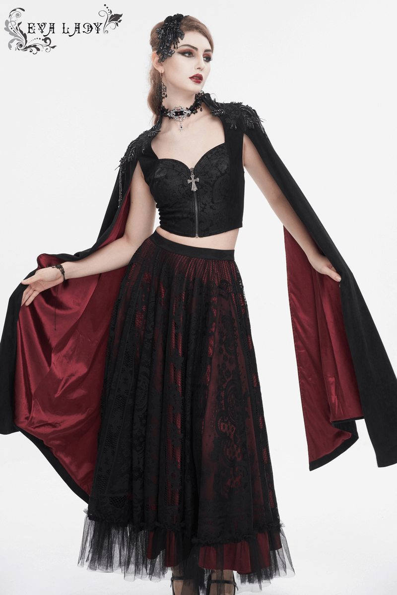 Woman in gothic outfit featuring a black crop top with cape and a long red and black skirt, perfect for alternative fashion.
