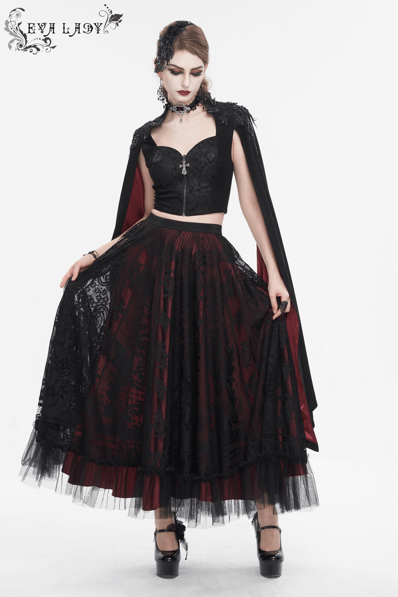 Gothic elegance: woman in a black crop top with cape and long red skirt, showcasing alternative fashion style.
