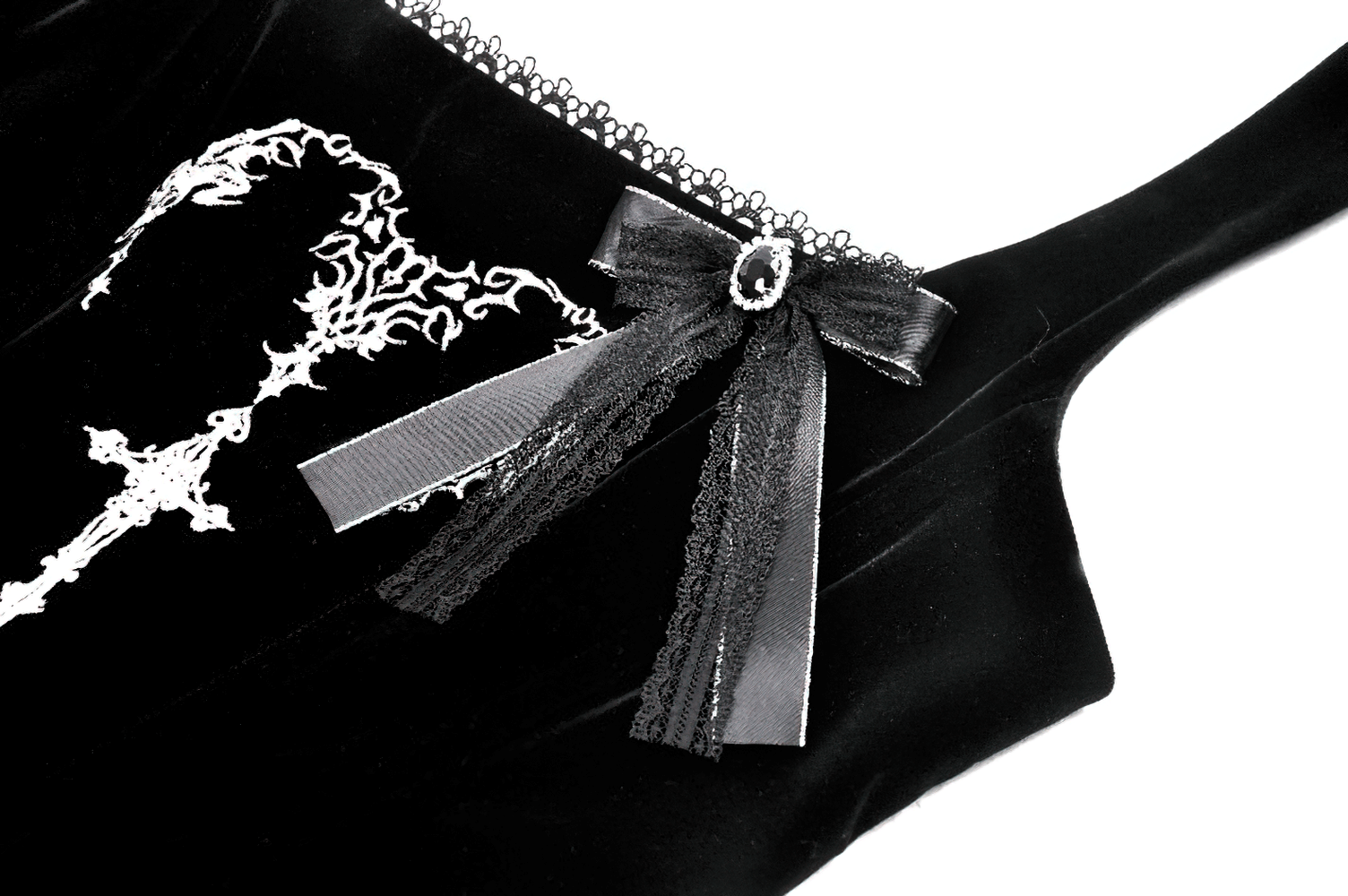 Close-up of intricate lace detailing and bow on black velvet gothic dress, showcasing stylish corset design.