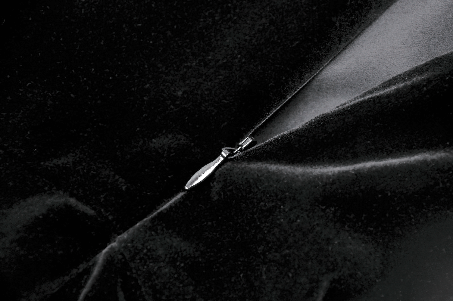 Close-up of silver zipper detail on stylish black velvet fabric, showcasing gothic dress design.