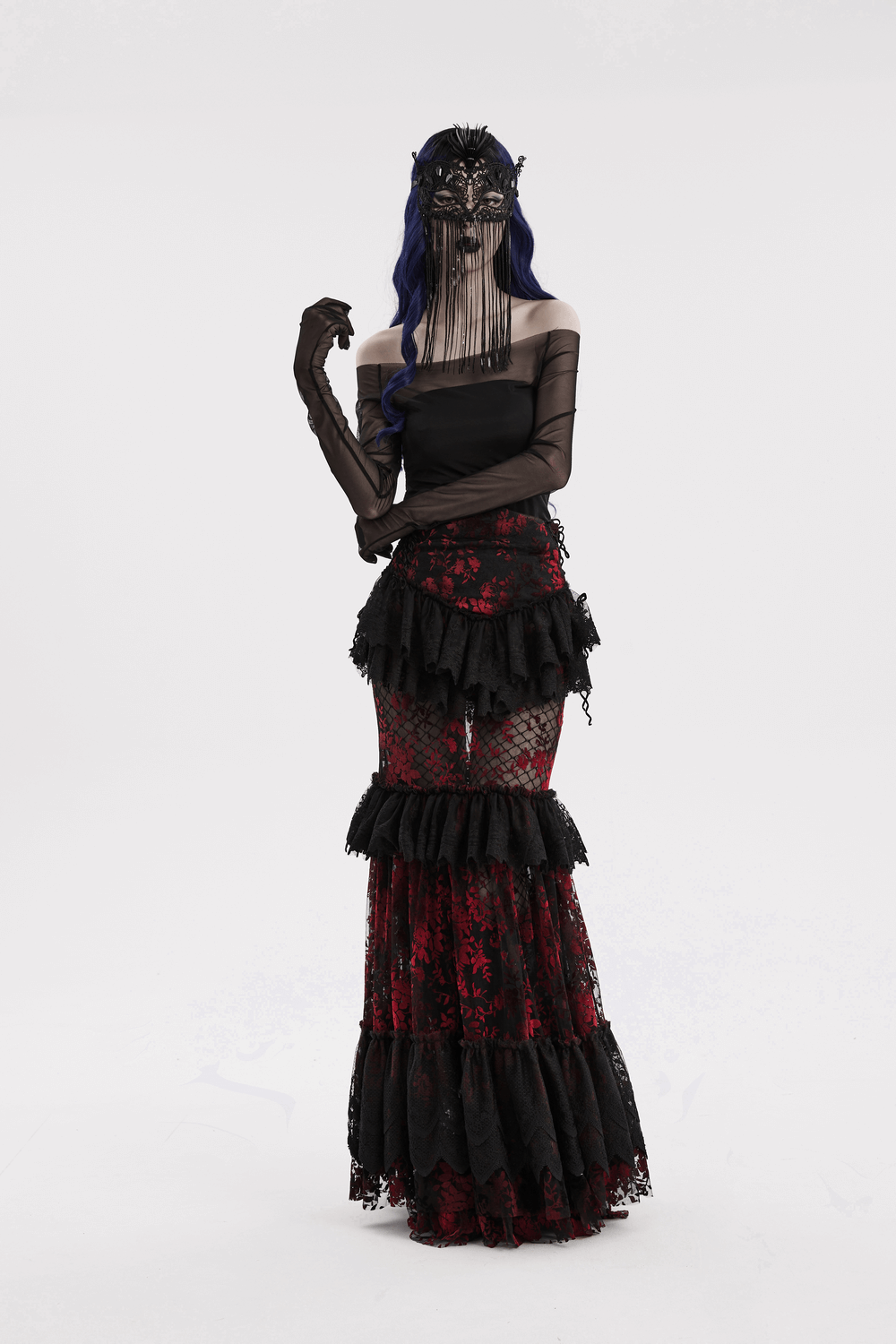 Gothic model in lace eye mask and dramatic black and red layered gown, exuding an enchanting aura.