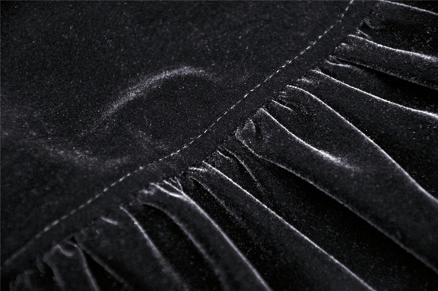 Close-up of luxurious black velvet fabric with delicate ruching, perfect for an enchanting cape.