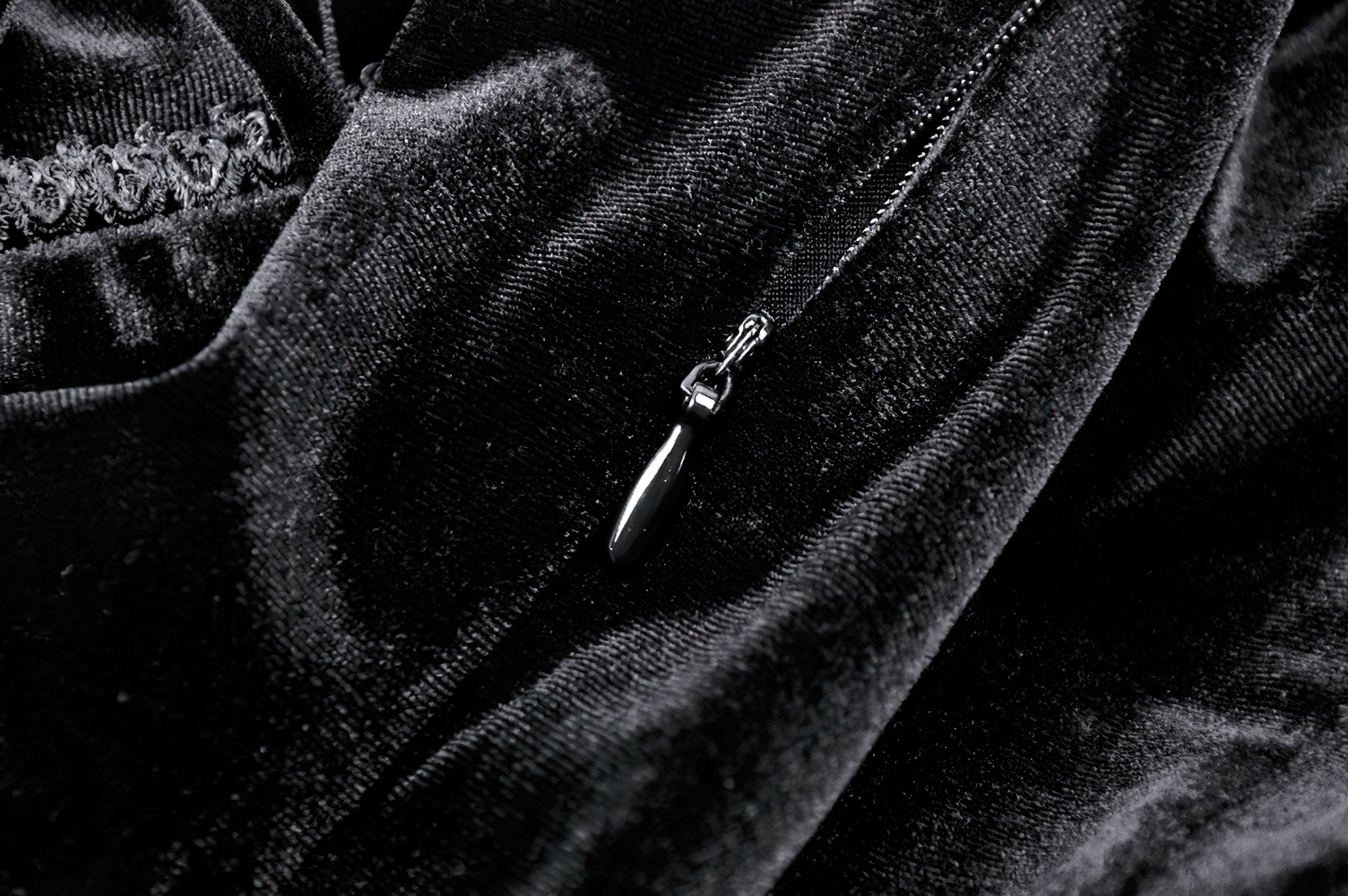 Close-up of black velvet fabric with a delicate silver necklace featuring a pointed pendant.