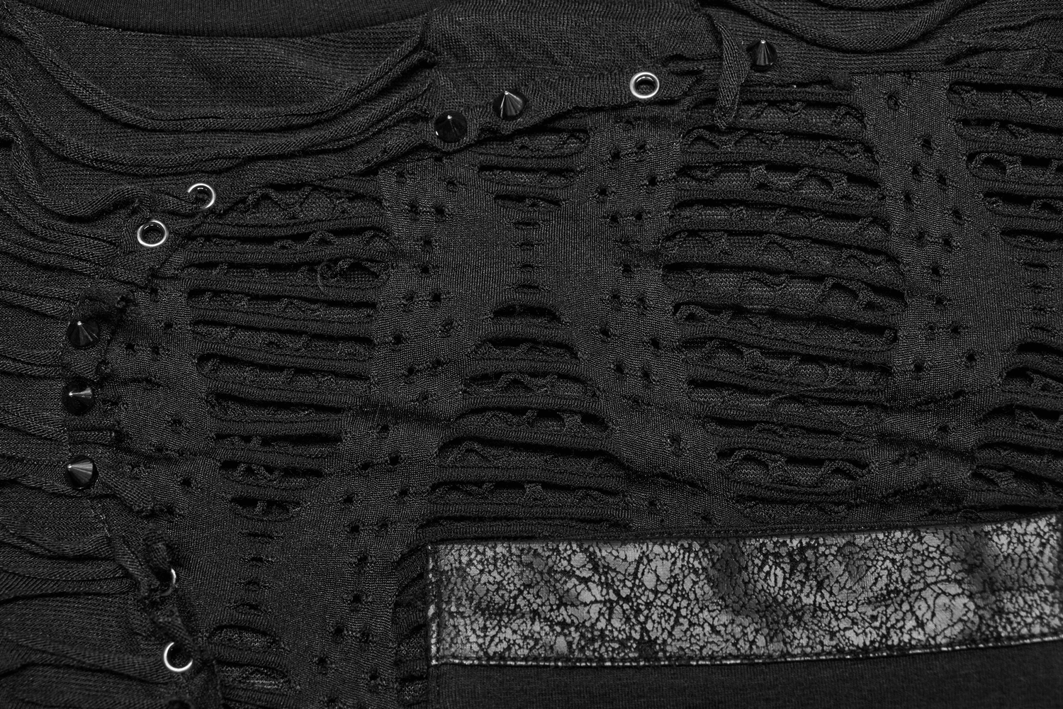 Close-up of black punk T-shirt featuring eyelet studs and bold mesh splice design for an edgy look.