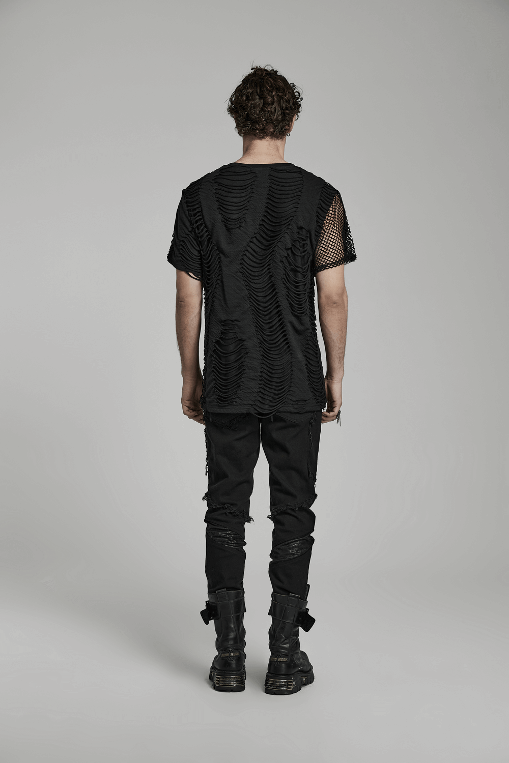 Back view of a black eyelet-studded punk T-shirt with mesh splice design, paired with black distressed pants.