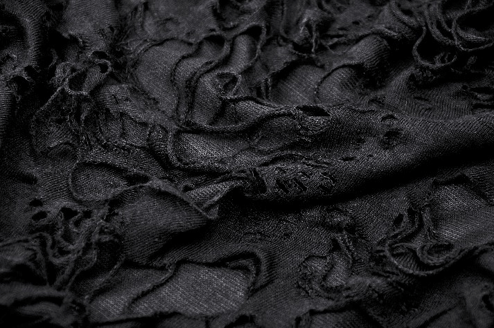 Close-up of black distressed mesh fabric showcasing asymmetrical rips and textures for gothic fashion.