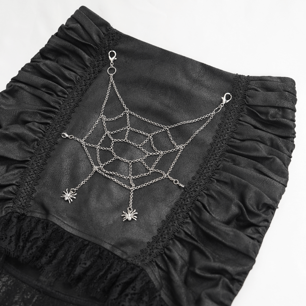 Close-up of black spider web gothic skirt detailing with silver chain and spider charms on asymmetric design.