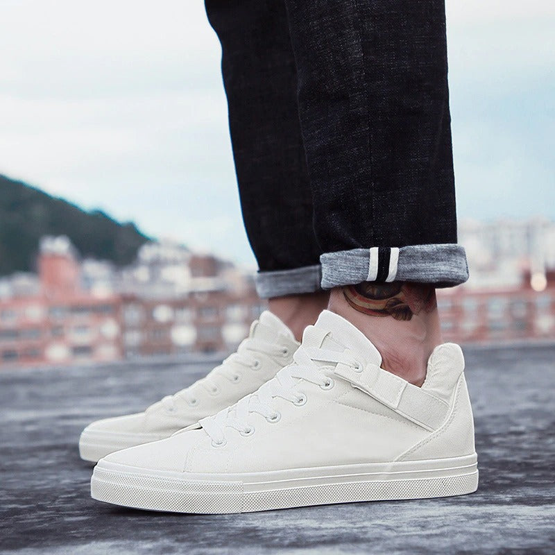 Breathable white canvas men's casual sneakers paired with rolled denim for a stylish street look.