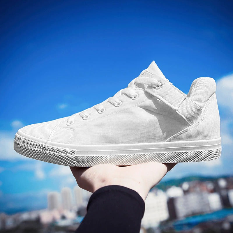 White canvas sneakers held against a blue sky, showcasing breathable design for casual street style.